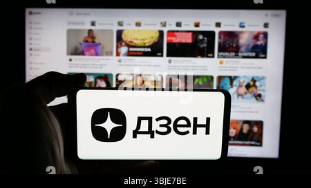 Dans cette illustration photo, une personne tient un téléphone portable avec le logo de la plate-forme russe d'agrégation de contenu Dzen.ru sur l'écran en face de la page Web. Banque D'Images