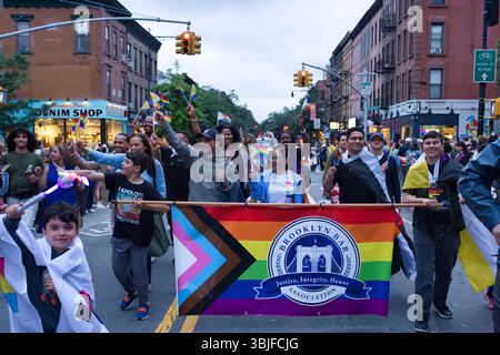Un défilé dynamique LGBTQ+ Pride mettant en vedette un groupe diversifié de personnes tenant des drapeaux arc-en-ciel et une grande bannière de la Brooklyn Bar Association. La scène Banque D'Images