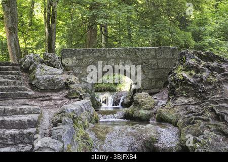 Un vieux petit pont de pierre sur le Bruehlbach, ruisseau sauvage et romantique et source de la cascade Urach dans une forêt dense, Bad Urach Banque D'Images