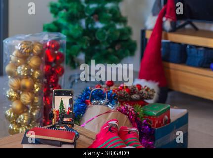 Gros plan de la scène festive avec sapin de Noël artificiel, boîtes d'ornements, guirlandes et cadeaux créant une atmosphère chaleureuse de nouvel an et de vacances Banque D'Images