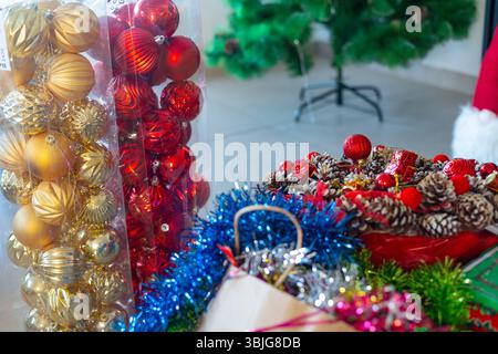 Gros plan sur les boules de Noël, les pommes de pin et les guirlandes colorées dans l'emballage sur le sol avant de décorer l'arbre, préparation festive Banque D'Images