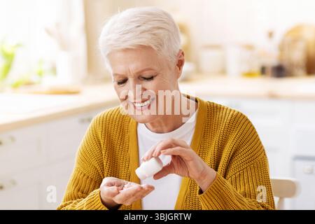 Bonne vieille dame en utilisant des suppléments, cuisine intérieure Banque D'Images