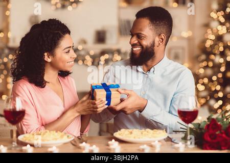 Jeune homme noir échangeant des cadeaux avec sa femme heureuse Banque D'Images