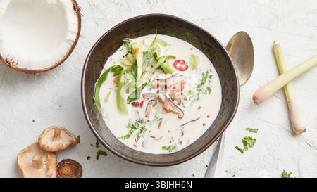 Soupe Tom Kha Gai dans un bol – une soupe crémeuse thaïlandaise à la noix de coco avec du poulet, du citron vert, de la citronnelle et des champignons, parfaite comme un déjeuner chaud. Banque D'Images