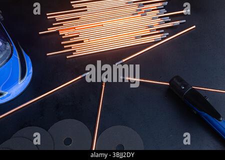 Électrodes de gougeage avec support, masque de soudage et disques abrasifs sur fond noir. Outils de soudage isolés noirs. Banque D'Images