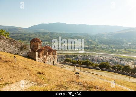 Berat, Albanie 5-07-2024 : citadelle historique de Berat avec des maisons ottomanes blanches escaladant la colline, des rues en pierre et la montagne en toile de fond Banque D'Images