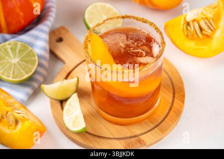 Margarita de Thanksgiving, cocktail d'arbustes de citrouille douce, boisson d'automne savoureuse à l'alcool sur fond blanc avec des tranches de citrouilles, espace de copie Banque D'Images