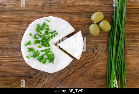 Camembert au fromage, olives et oignon vert sur une vieille table en bois. Vue de dessus Banque D'Images