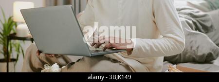 Homme travaillant sur ordinateur portable dans un environnement domestique confortable Banque D'Images