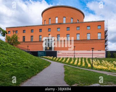Stockholm, Suède - 11 mai 2025 : un bâtiment architectural moderne avec un sommet rond, avec une façade rougeâtre-orange. La structure est entourée par Banque D'Images