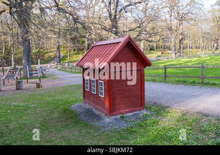 Une petite maison en bois rouge qui est une poubelle pour le Banque D'Images
