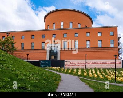 Stockholm, Suède - 11 mai 2025 : un bâtiment architectural moderne avec un sommet rond, avec des murs orange et de grandes fenêtres. Le premier plan comprend Banque D'Images