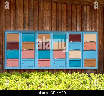 Stockholm, Suède - 11 mai 2025 : un ensemble coloré de boîtes aux lettres montées sur un mur en bois, avec différentes nuances de bleu, rose, orange et beige. Th Banque D'Images