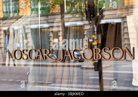 Stockholm, Suède - 11 mai 2025 : une vitrine de magasin affichant des vêtements avec le nom 'Oscar Jacobson' en évidence. Le reflet du Banque D'Images