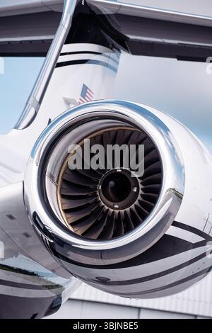 Gros plan d'un moteur à réaction sur un avion d'affaires de luxe avec queue en T, photographié sous un ciel lumineux. Pales de turboréacteur et nacelle polie dans les détails nets. Banque D'Images