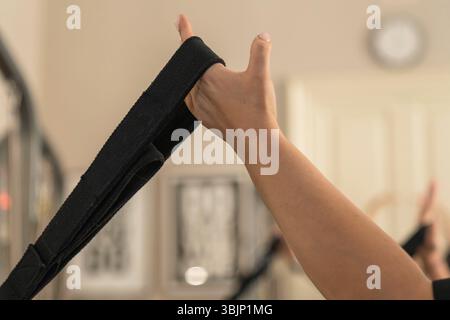 Gros plan de la main d'une femme forte saisissant une poignée pour un exercice de suspension ou de résistance dans un studio de fitness. Concentrez-vous sur la puissance et l'effort. Banque D'Images
