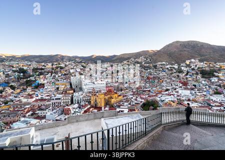 Un homme regarde la ligne d'horizon des bâtiments aux couleurs pastel dans la capitale de Guanajuato City, Guanajuato, Mexique depuis la colline de San Miguel. La ville classée au patrimoine mondial de l'UNESCO est construite dans une vallée étroite avec des escaliers sur les flancs des montagnes et connue pour sa charmante architecture coloniale espagnole. Banque D'Images