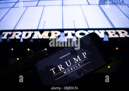 SLC, UT – 16 juin 2025 : un homme tient un smartphone affichant le logo Trump Mobile, avec une bannière Trump Mobile floue vue en arrière-plan. Banque D'Images
