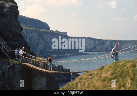Les gens traversent Carrick-A-Rede Rope Bridge, Ballycastle, comté d'Antrim, Irlande du Nord. Août 1993 Banque D'Images
