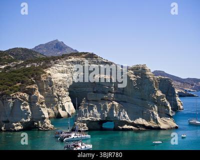 Vue verticale des célèbres grottes Kleftiko sur l'île de Milos, montrant des bateaux dans la baie et la verdure côtière. Banque D'Images