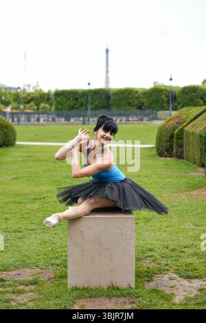 Ballerine assise sur piédestal en tutu noir souriant à l'extérieur Banque D'Images