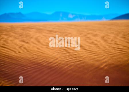 Texture des dunes de sable doré avec ondulations et montagnes perspective basse du sol Banque D'Images