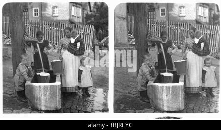 Femmes allant chercher de l'eau, années 1920, femmes et enfants à la pompe à eau dans la cour, montrant la scène quotidienne, noir et blanc, photo historique Banque D'Images