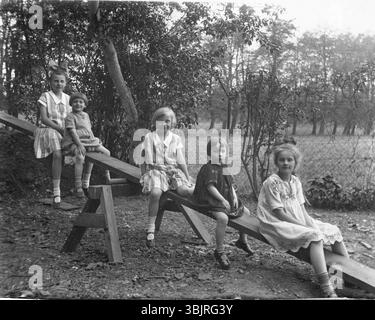 Cinq enfants sur une balançoire, années 1920, cinq enfants assis sur une balançoire à l'extérieur, photographie en noir et blanc, photographie historique Banque D'Images