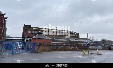 Vieux complexe de brasserie en briques à Édimbourg avec graffitis, murs altérés et signes de décomposition urbaine, toujours en usage dans un cadre industriel graveleux. Banque D'Images