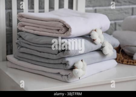 Pile de draps propres avec des fleurs de coton sur la table près du mur de briques grises dans la chambre Banque D'Images