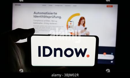Stuttgart, Allemagne - 2025 : personne tenant un téléphone portable avec le logo de la société de vérification d'identité IDnow GmbH sur l'écran en face de la page web. Banque D'Images