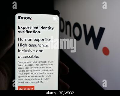 Stuttgart, Allemagne - 2025 : personne tenant un téléphone portable avec la page web de la société de vérification d'identité IDnow GmbH sur l'écran devant le logo. Banque D'Images