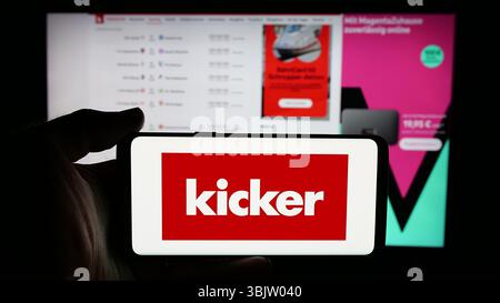 Stuttgart, Allemagne - 04-17-2025 : personne tenant un téléphone portable avec le logo du magazine allemand de football et de sport Kicker sur l'écran devant la page web. Banque D'Images