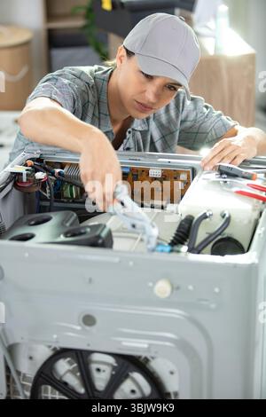 femme technicien répare le lave-linge Banque D'Images