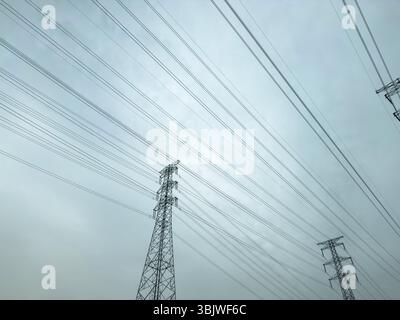 Réseau de lignes électriques et tours de transmission en acier hautes sur fond de ciel nuageux, infrastructure énergétique Banque D'Images