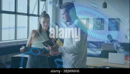 Collaboration de collègues analysant la tablette et le dossier vert dans un bureau ouvert, avec ordinateur portable Banque D'Images