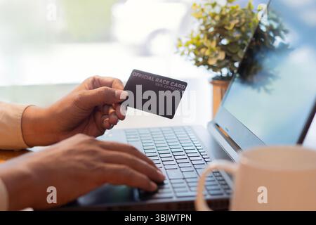 Vue latérale de l'homme d'affaires dans le bureau, en utilisant la carte de crédit pour payer en ligne avec ordinateur portable. Gros plan, mise au point sélective. Concept de paiement en ligne. Banque D'Images