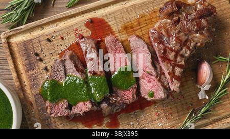 steak tranché fraîchement grillé avec sauce persil vert sur planche à découper en bois, vue de dessus Banque D'Images