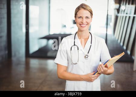 Stéthoscope et classeur reposant sur le sol en béton près des cloisons de verre dans le couloir de la clinique Banque D'Images