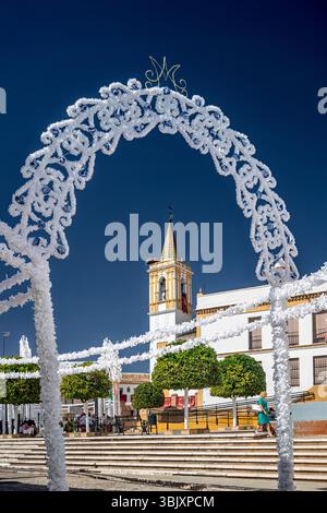 Des arcs en bois ornés de papier vibrant préparent la place pour les festivités honorant la Vierge du Rosaire à Carrión de los Céspedes. Banque D'Images