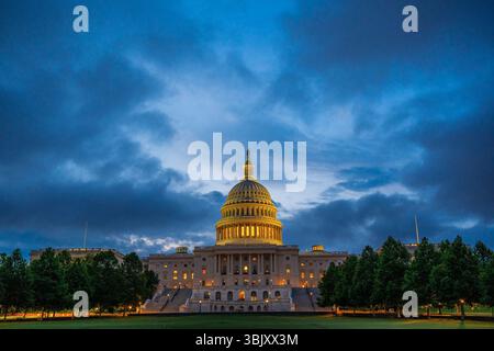 Le bâtiment du Capitole des États-Unis brille d'une lumière jaune chaude à l'aube à Washington, DC, debout contre un ciel bleu profond dans le calme de tôt le matin. Banque D'Images