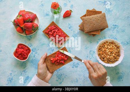 Seigle croustillant avec confiture de fraises. Toast aux fraises sur pain de seigle. Petit déjeuner sucré végétarien sur fond bleu Banque D'Images