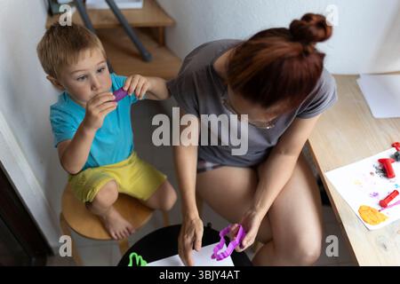 Mère et fils se relaxant à la maison, jouant avec de l'argile à modeler Banque D'Images