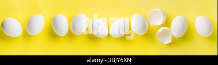 Beaucoup d'œufs de poule blancs couchés en rangée sur un fond jaune tendance. Composition créative minimale de Pâques avec espace de copie. Ressort Banque D'Images