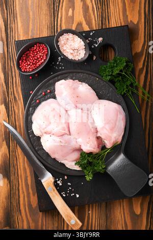 Filet de cuisse de poulet cru sans peau avec des herbes et des épices sur fond de vieux bois. Viande de volaille de ferme. Vue de dessus avec copie spac Banque D'Images