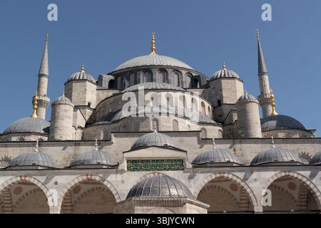 Les visiteurs admirent les détails complexes et le design grandiose de la mosquée bleue d'Istanbul tout en se prélassant dans la chaleur du soleil de la journée. Banque D'Images