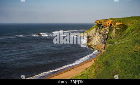 Paysage côtier à couper le souffle présentant des falaises imposantes, des vagues écrasantes et une plage de sable à Whitby, au Royaume-Uni Banque D'Images