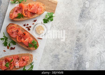 Sandwichs au saumon salé. Ouvrez les sandwichs à partir de pain de céréales ou de seigle à grains entiers avec saumon salé, graines de sésame et t séché Banque D'Images