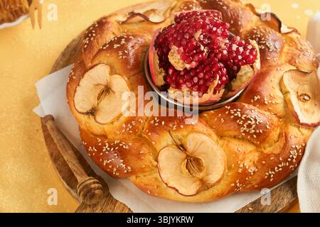 Fêtes juives - Rosh Hashanah ou Rosh Hashana. Grenade, pommes, miel et challah ronde sur fond de table jaune rustique. Banque D'Images