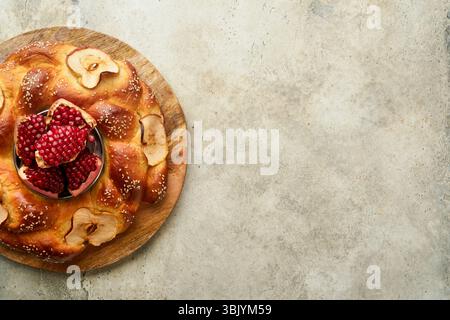 Fêtes juives - Rosh Hashanah ou Rosh Hashana. Grenade, pommes, miel et challah ronde sur fond de table gris rustique. J Banque D'Images